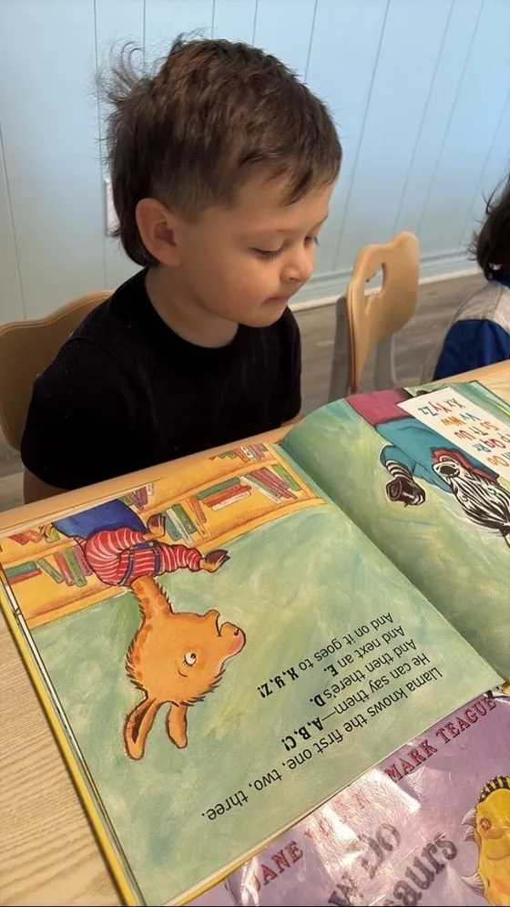 A child reading a picture book at Bright Haven